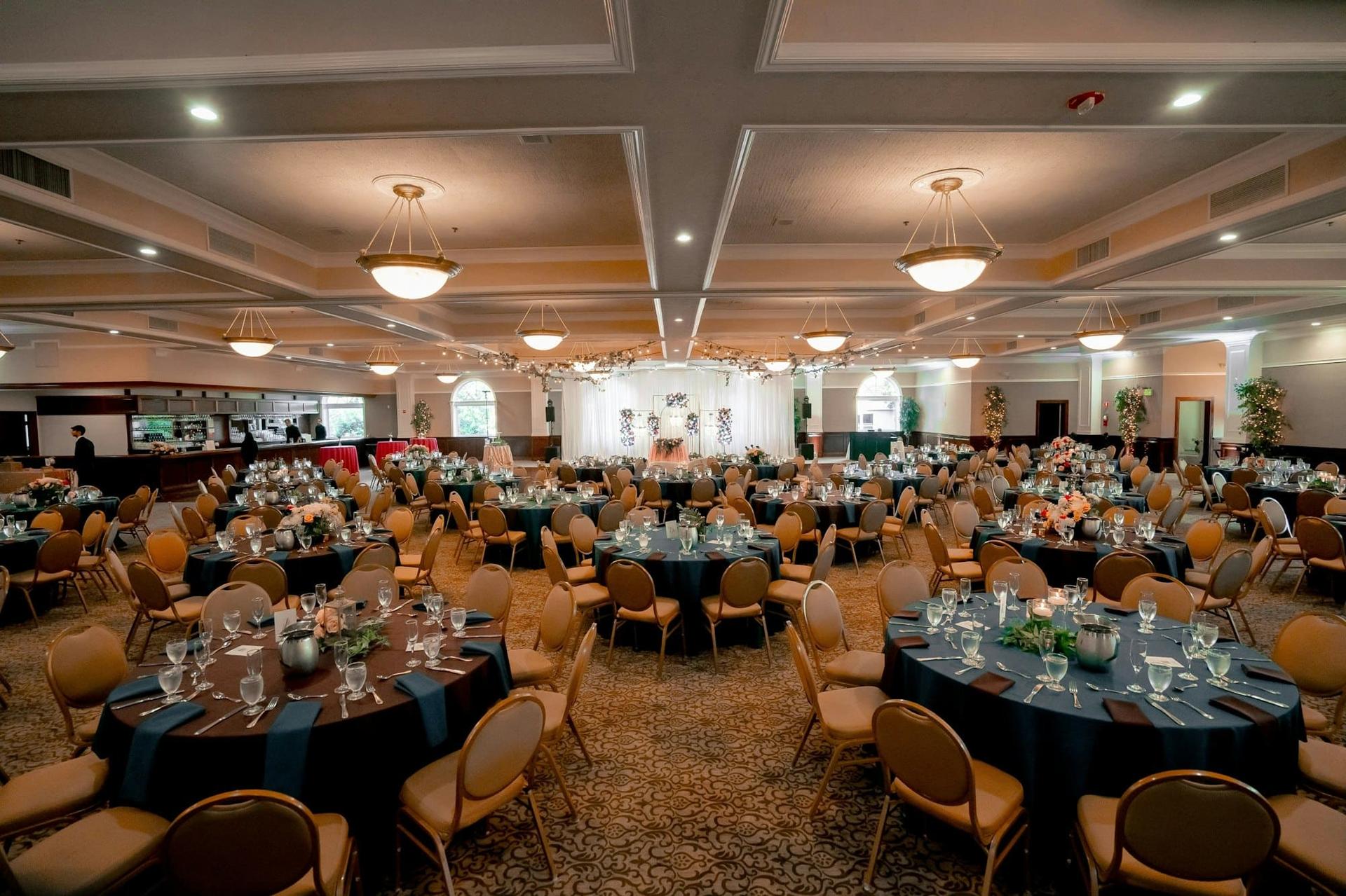 A large ballroom prepared with dozens of dressed round tables