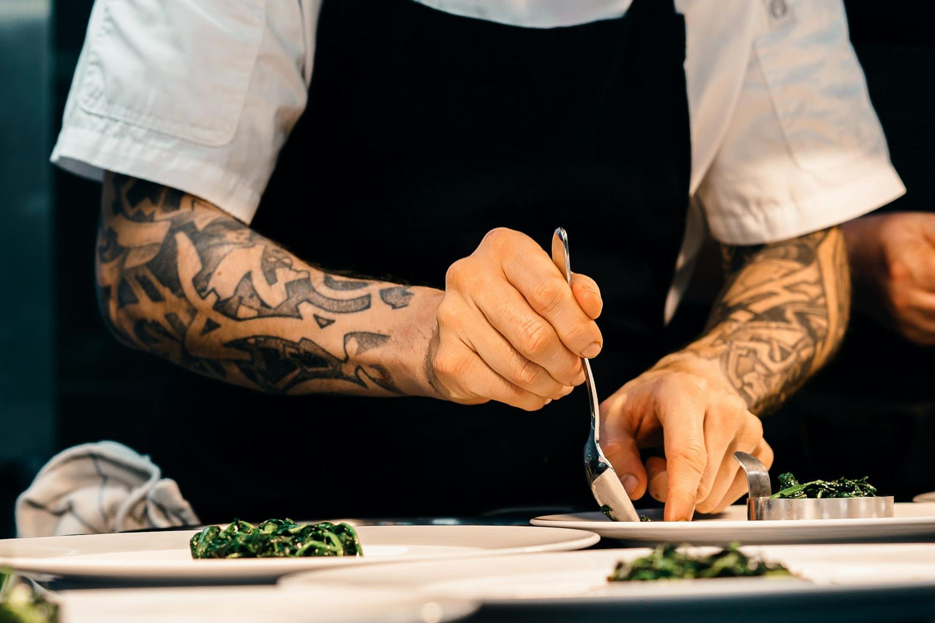 A chef plating a course with fine tweezers