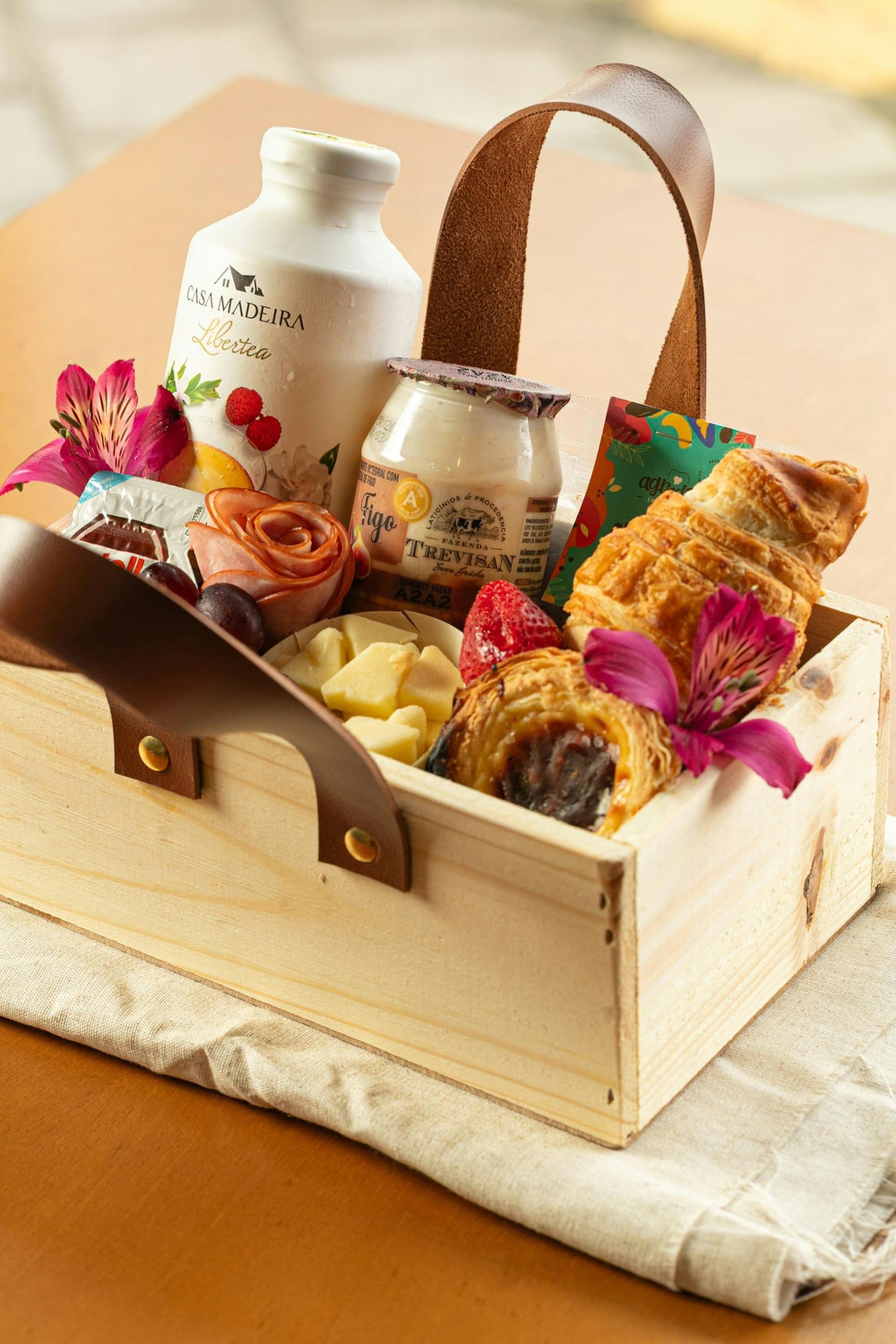 A wooden gift crate filled with pastries, preserves and flowers