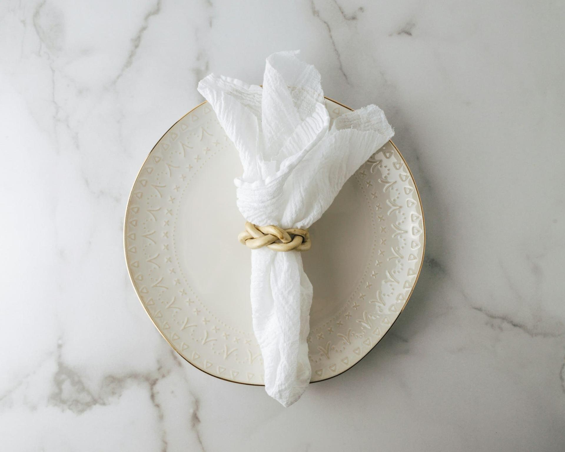 A linen napkin gathered in a gold ring on a gilt-edged plate